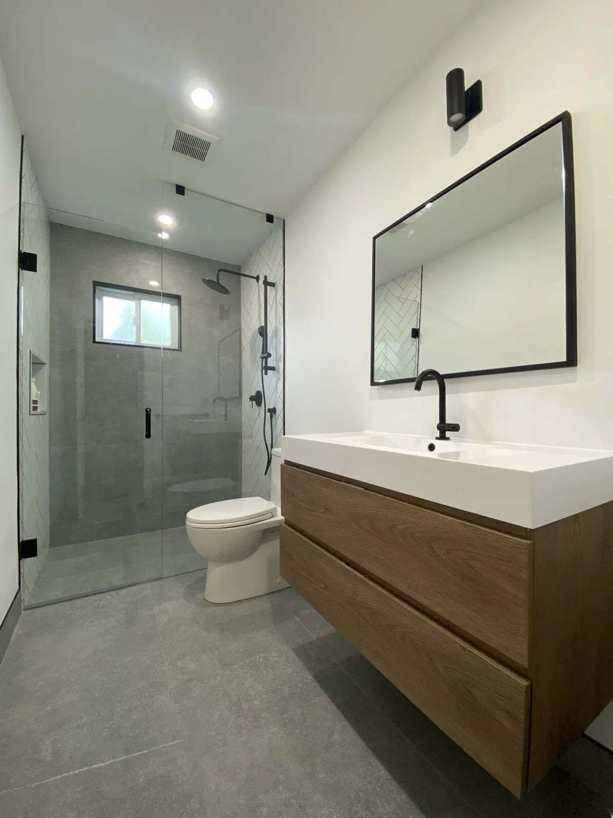 Walnut floating vanity beside a frameless glass shower