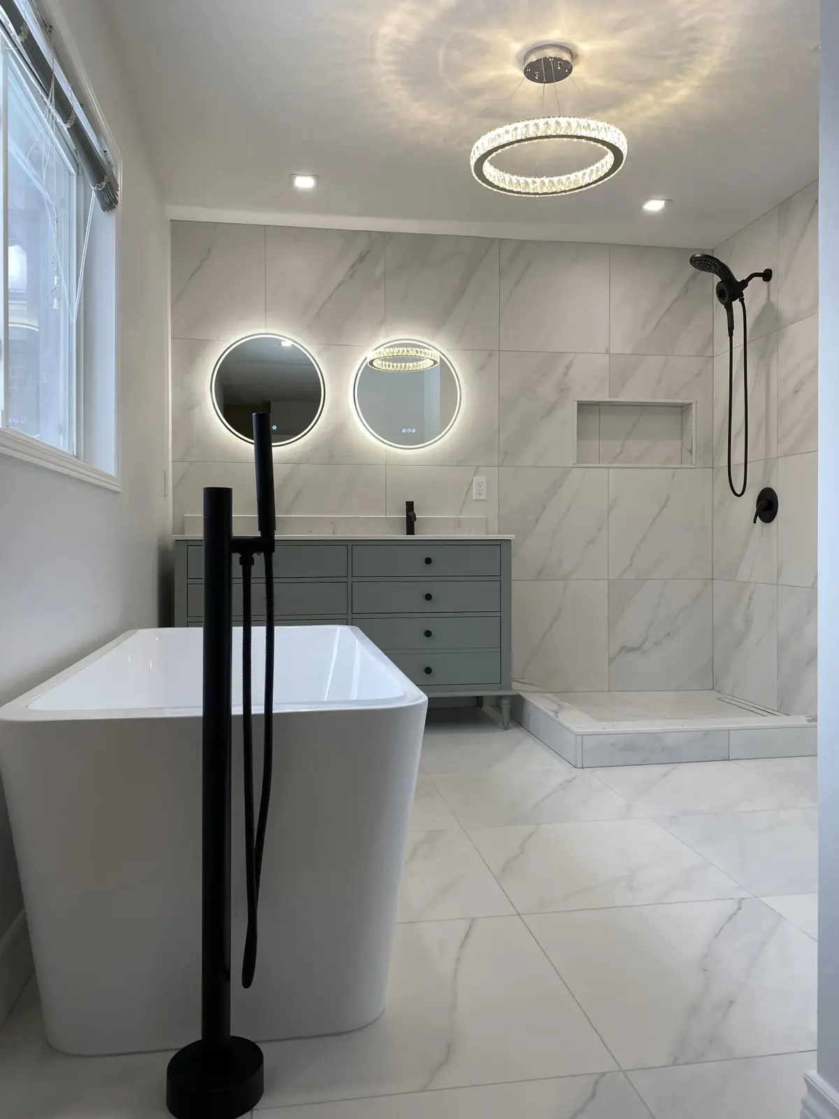 Freestanding tub with matte black filler in a marble bathroom