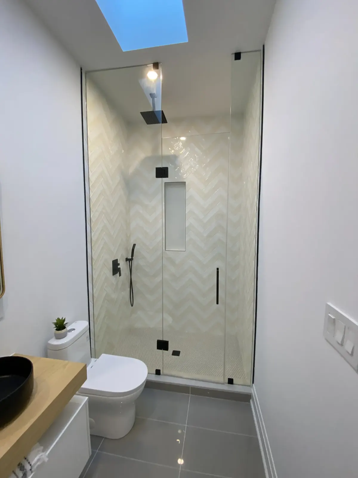 Glass shower under a skylight with herringbone tile