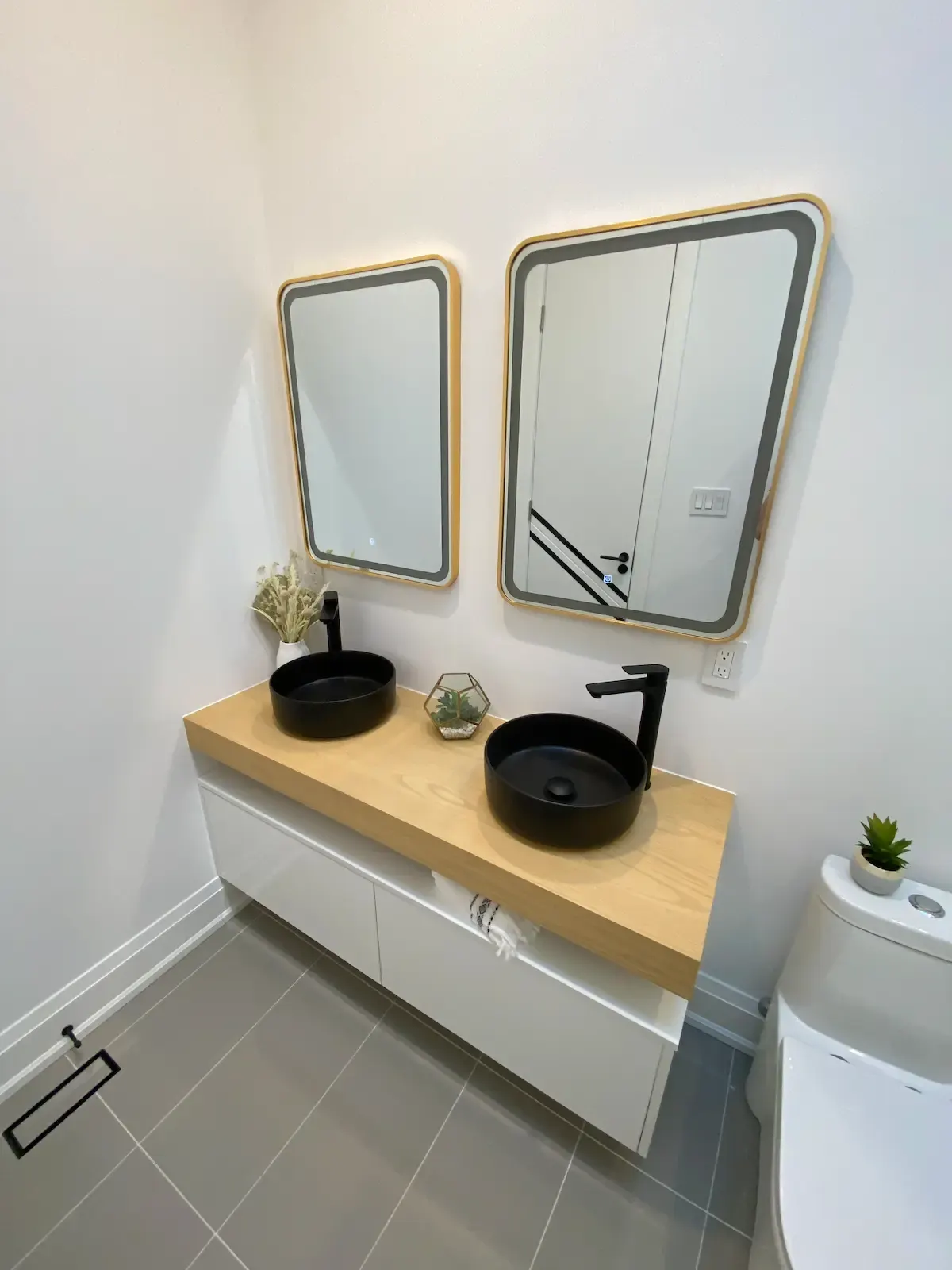 Twin vessel sinks on an oak top with backlit mirrors